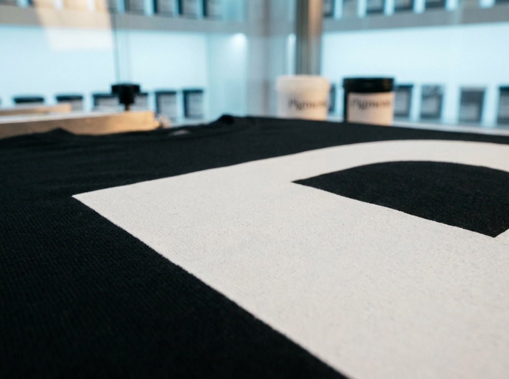 Close-up of a crisp white Pigmento print on a black garment in raking light