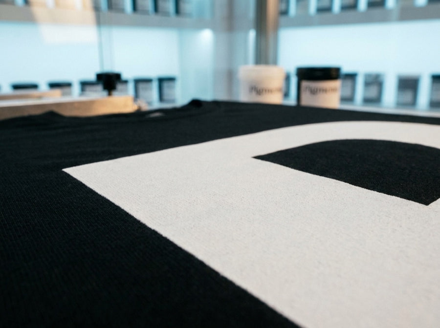 Close-up of a crisp white Pigmento print on a black garment in raking light