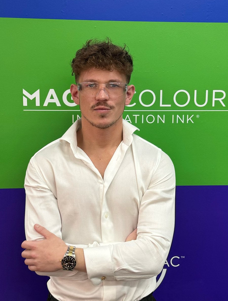 Sammy Chong, founder of Pigmento, standing in front of the Rutland Magna Colours ink banner